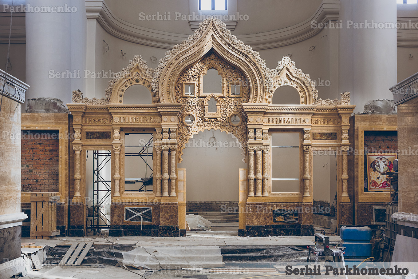 On-site assembly phase of a monumental carved yellow stone iconostasis inside a church by Serhii Parkhomenko's studio