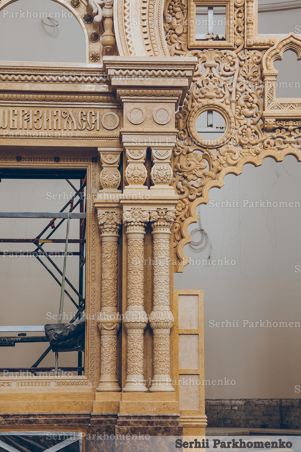 Ongoing on-site assembly of a monumental carved stone archway and ornate pillars