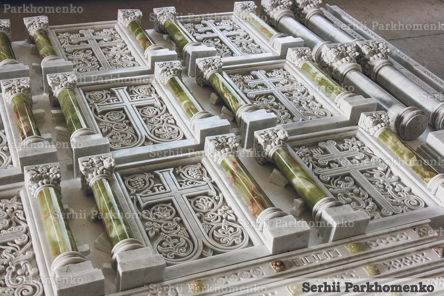 Massive layout of carved white marble altar panels and polished green onyx columns inside Serhii Parkhomenko's workshop