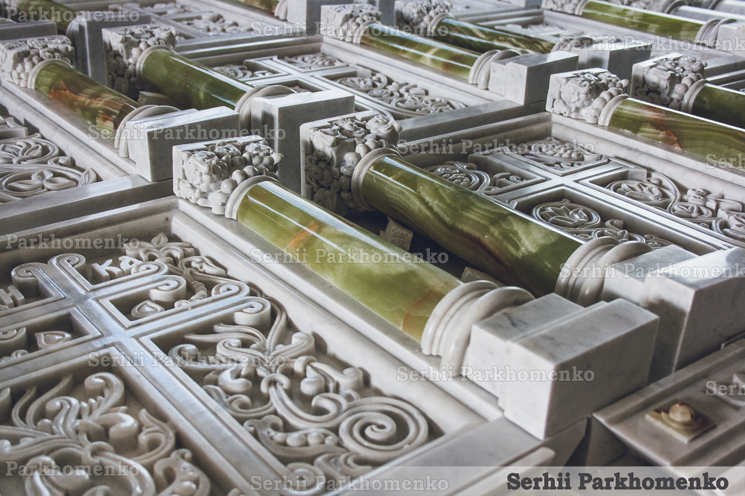 Close-up of a translucent polished green onyx pillar with an intricately carved marble capital and vine borders