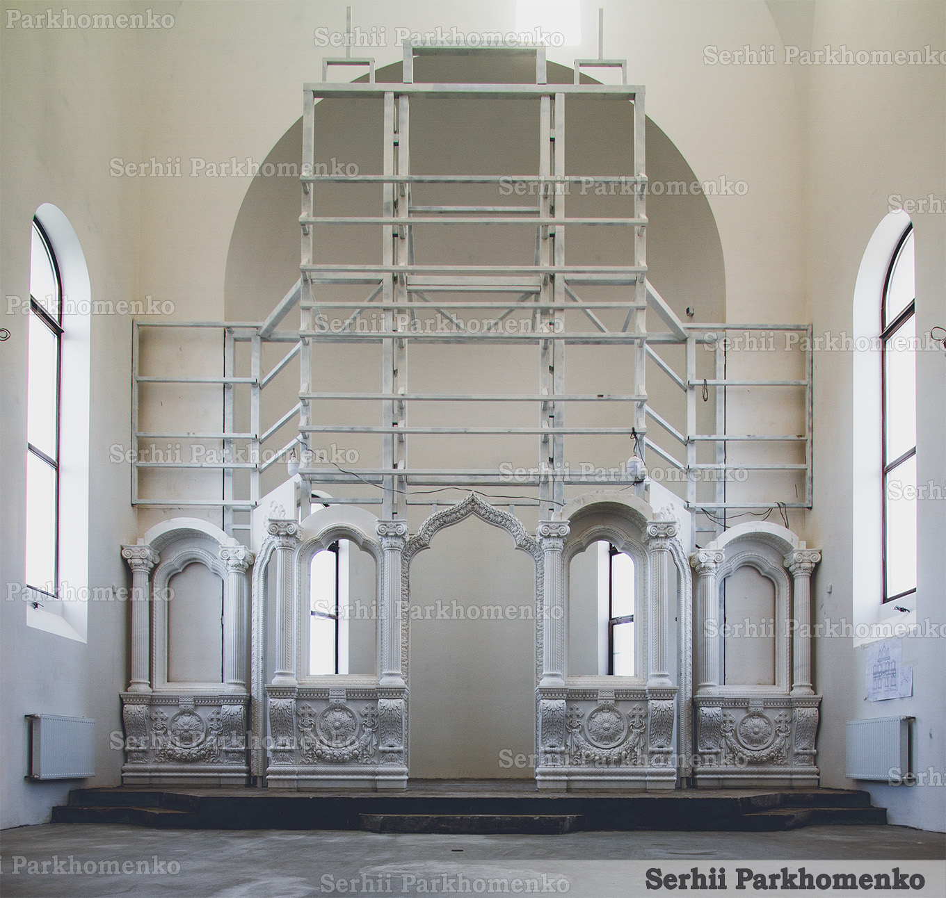 Initial on-site installation phase of the white marble iconostasis first tier inside the St. Sergius Chapel
