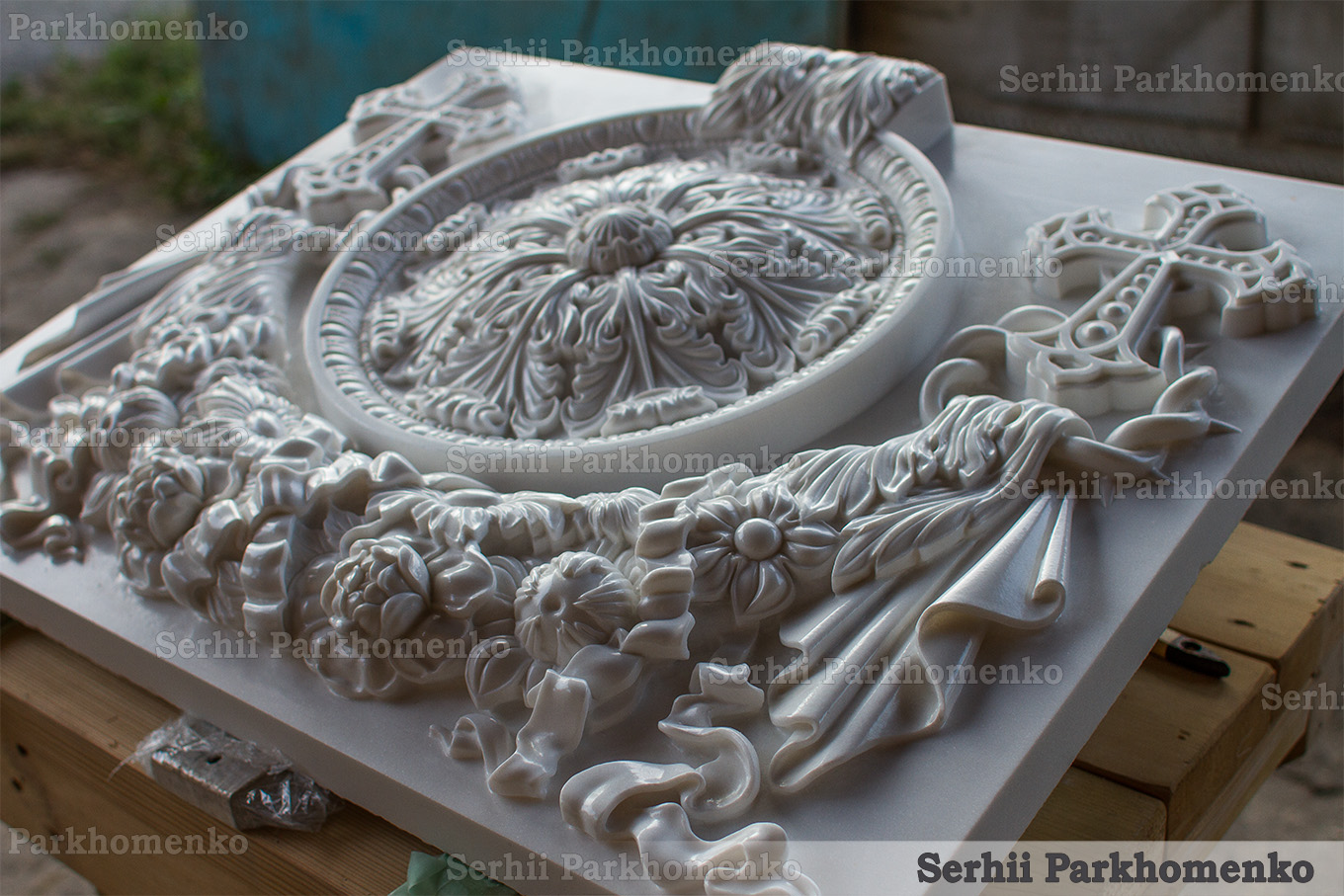 Angle perspective of an exquisitely carved white marble altar base plate showcasing spectacular depth, cascading flower festoons, and drapery