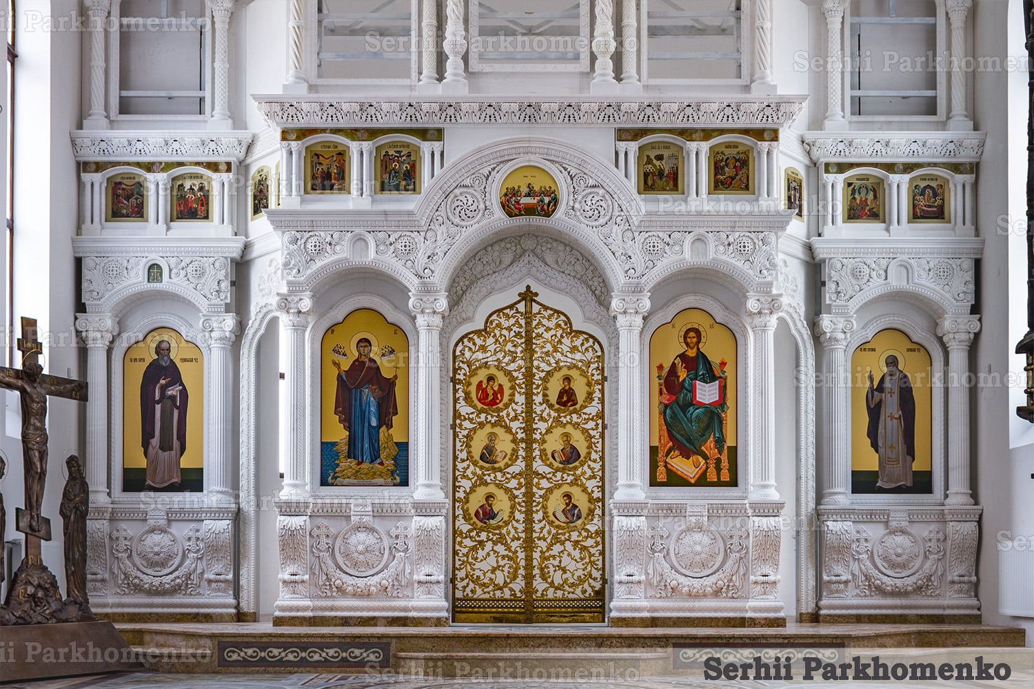 Completed first tier of the Greek white marble iconostasis with golden Holy Doors and integrated icons at the St. Sergius Chapel