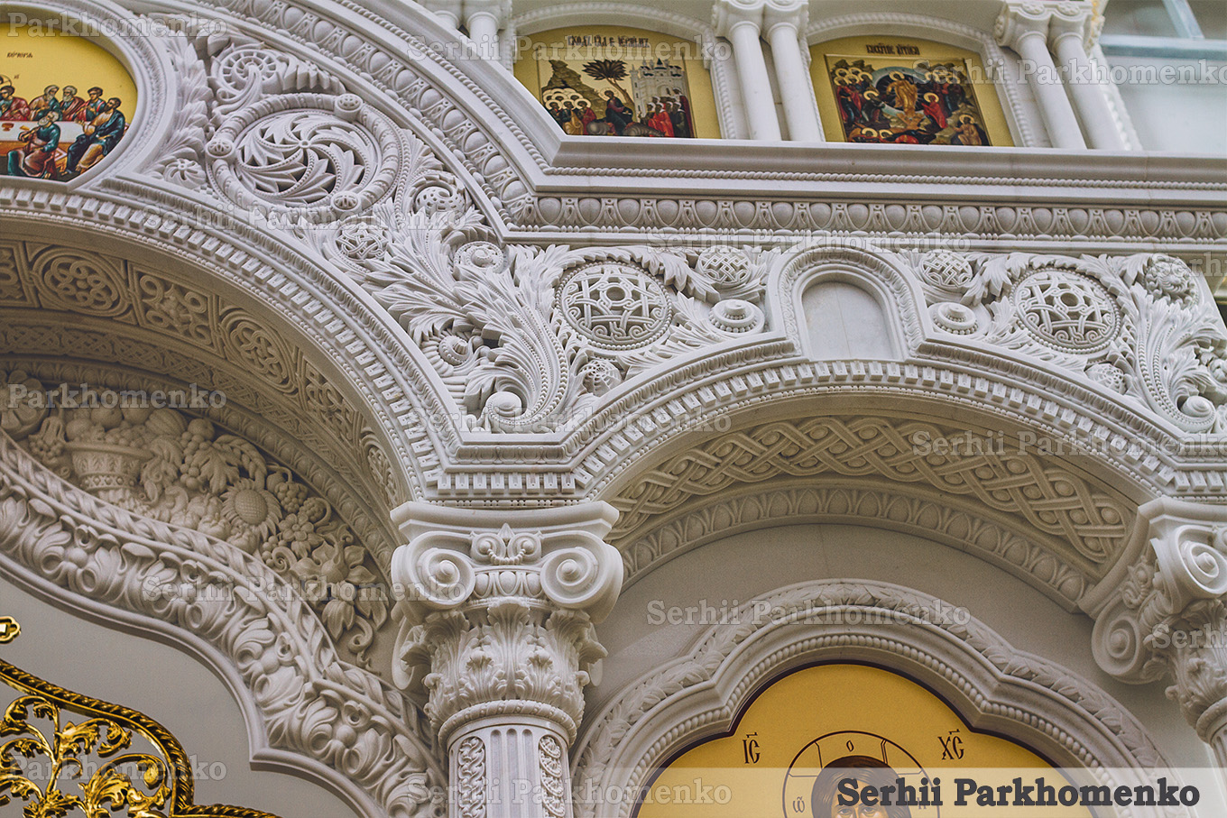 Close-up of a completed white stone church iconostasis with intricate classical carvings and columns by Serhii Parkhomenko's studio