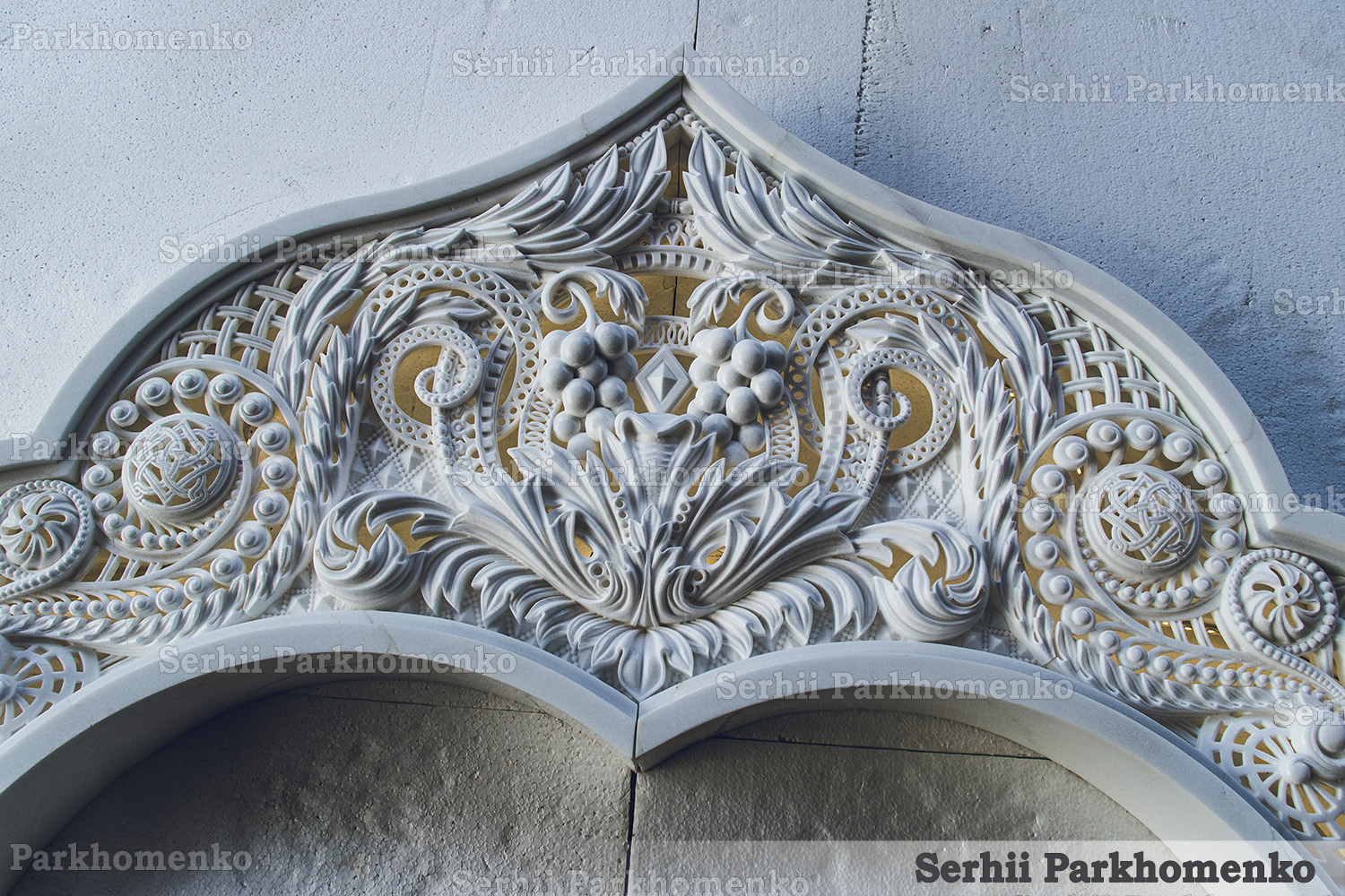 Close-up of the Neo-Byzantine stone relief detailing on a Thassos marble arch featuring grapevines and openwork lattices