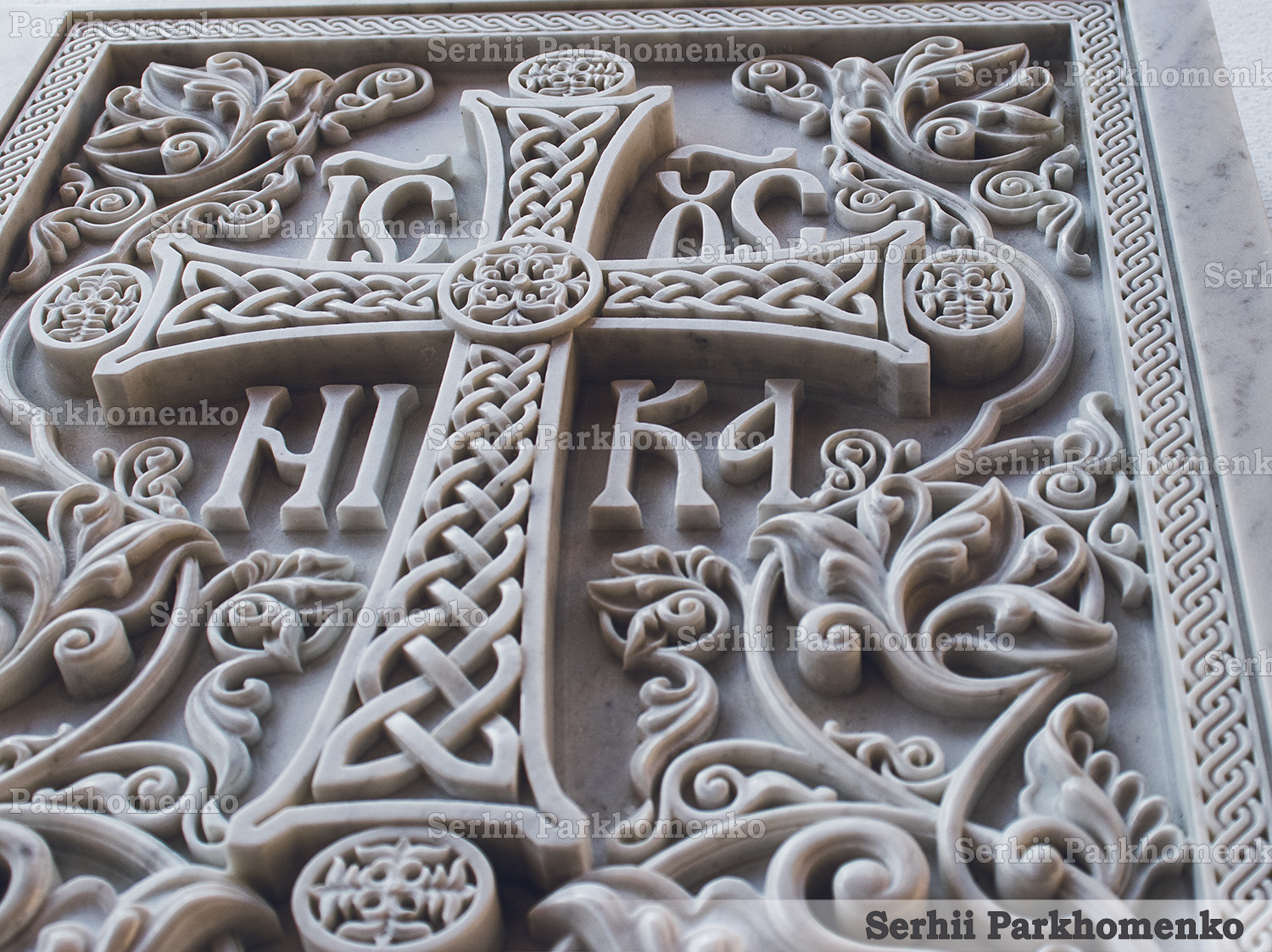 Close-up of high-relief Byzantine vine carvings and IC XC NI KA monogram on a white marble