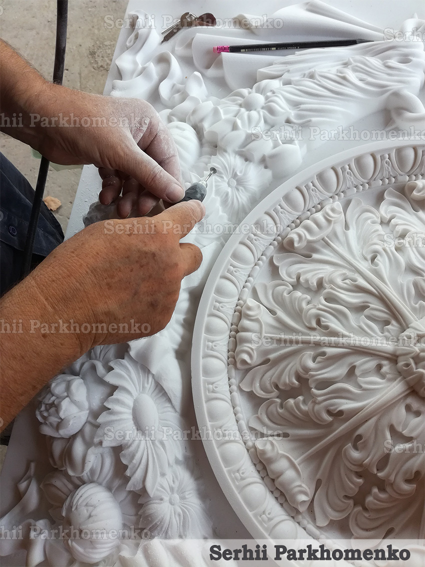 Artisan hand-carving and detailing an intricate marble relief rosette with a rotary tool at Serhii Parkhomenko's studio