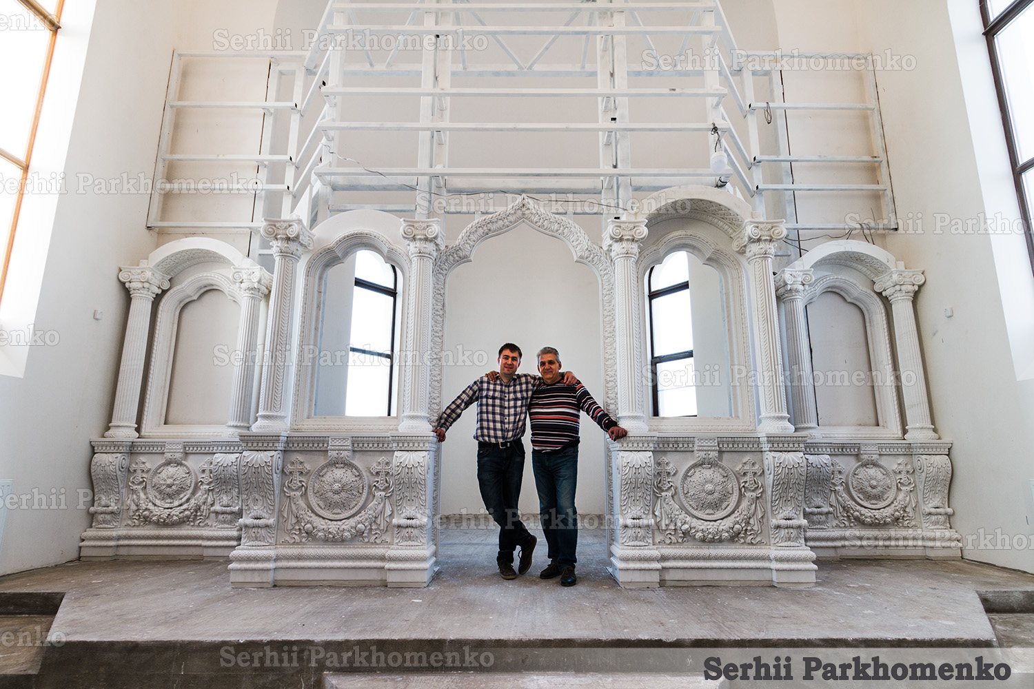 Ongoing on-site installation of a monumental carved stone iconostasis, with the first tier partially assembled by Serhii Parkhomenko's studio