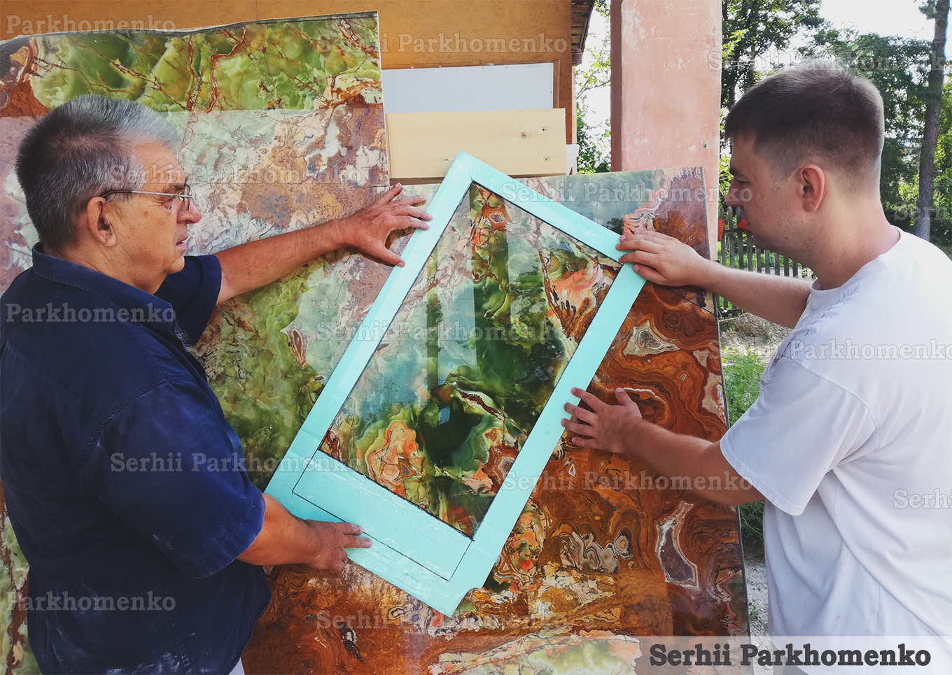 Master artisans using a frame template to select and layout the natural pattern on a polished luxury onyx stone slab