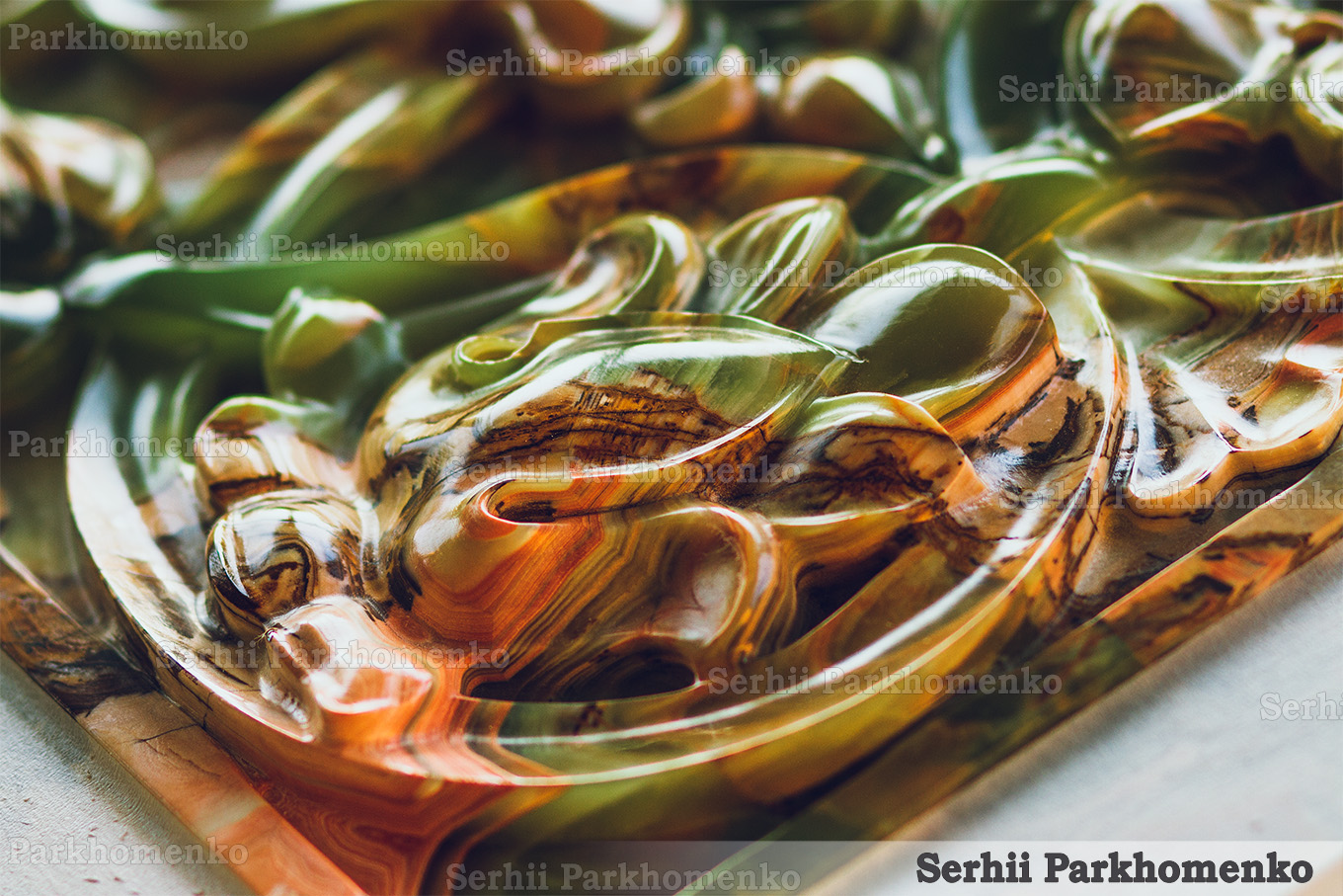 Close-up of a masterfully carved decorative element showcasing the translucent layers of natural green and orange onyx