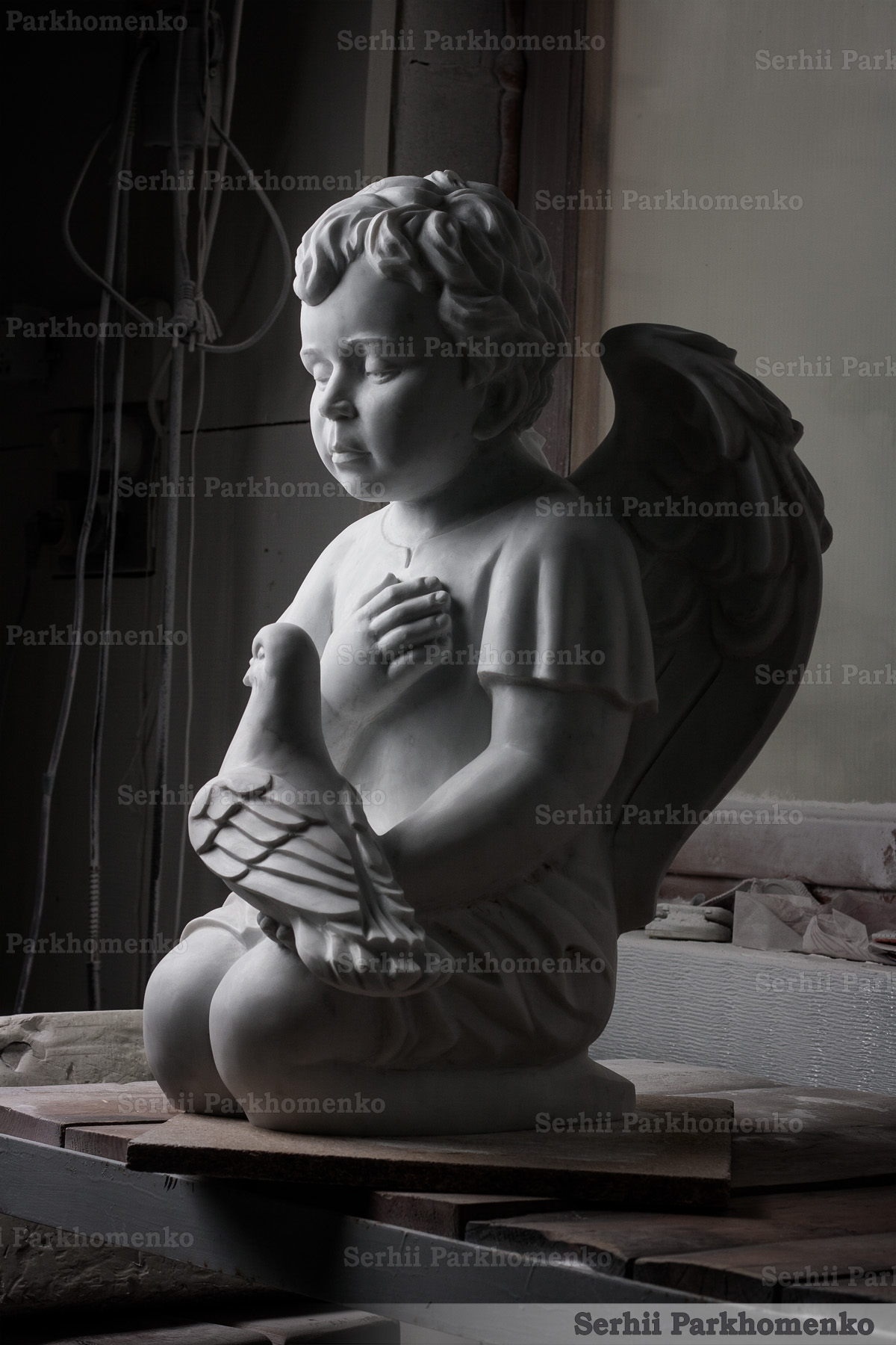 Side profile view of custom carved matte Bianco Carrara C marble angel with a dove by Serhii Parkhomenko's Studio