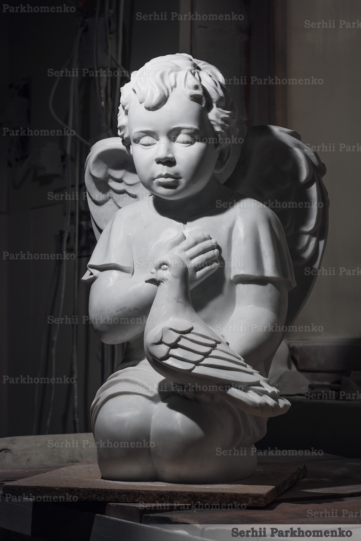 Front view of bespoke Bianco Carrara C stone cherub statue holding a dove with detailed wings
