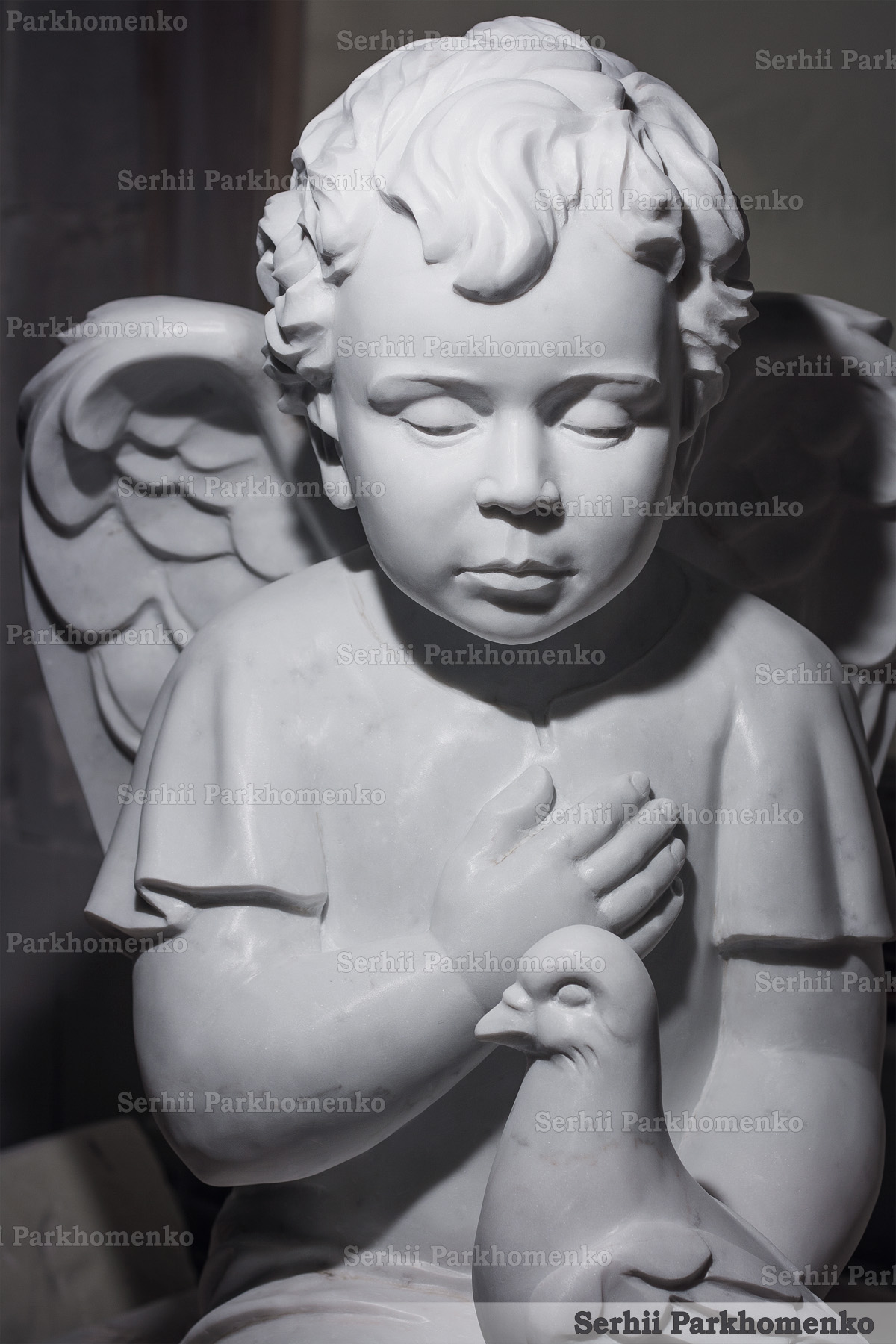 Exquisite hand-chiseled details on the face and garment of a matte finish marble angel monument
